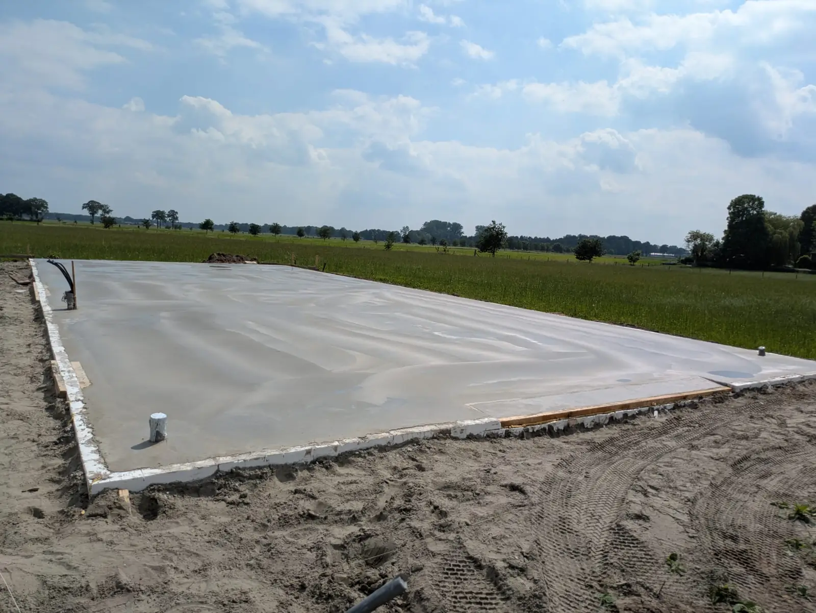 Grote betonnen fundering langs een weiland, klaar voor de opbouw